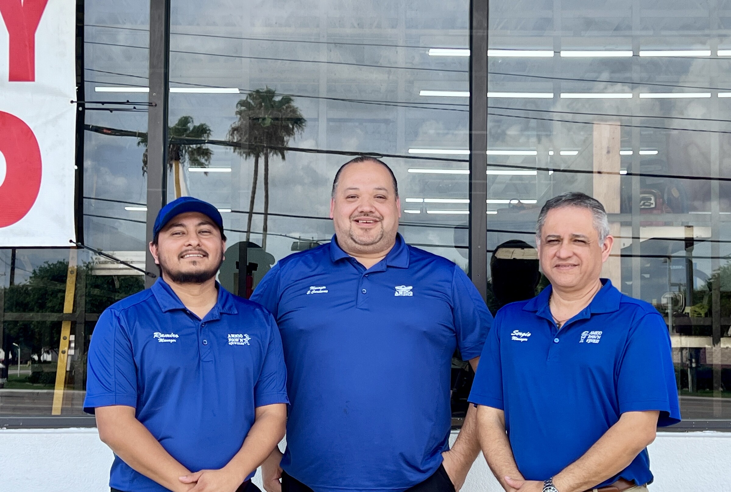 Three Amigo managers posing in front of the store windows